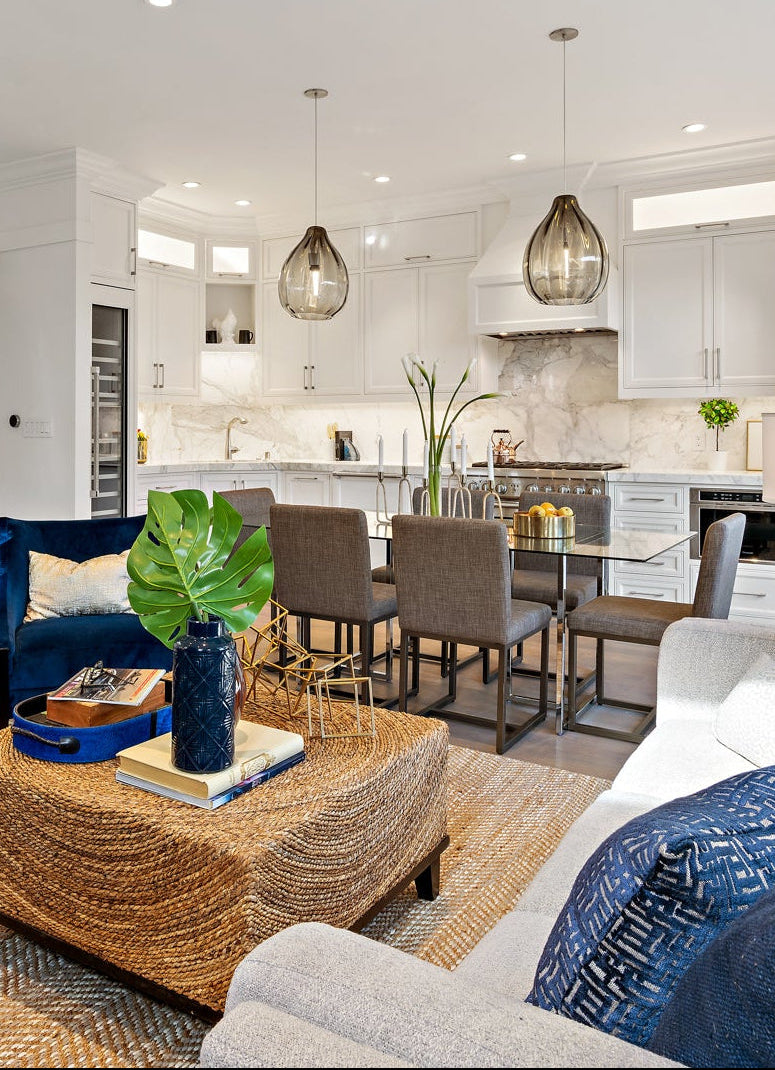 Modern living room with blue chairs, beige sofa, and kitchen in the background.