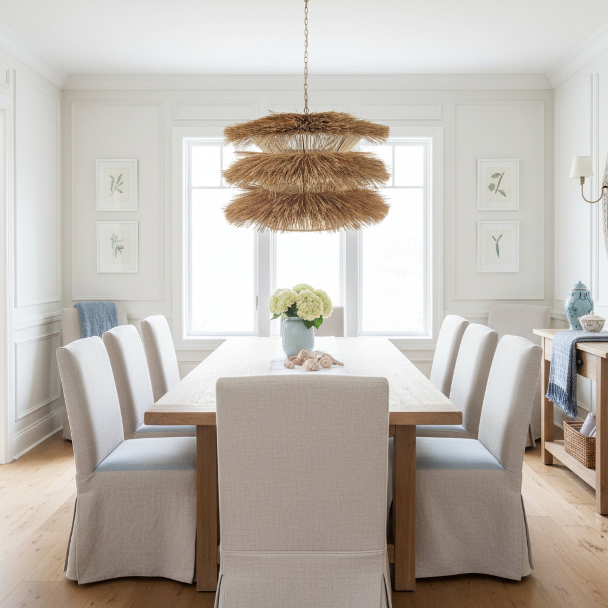 Decorative hanging light fixture with natural straw-like material on a white background.