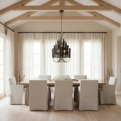Dining room with a long table and chairs under a modern chandelier.