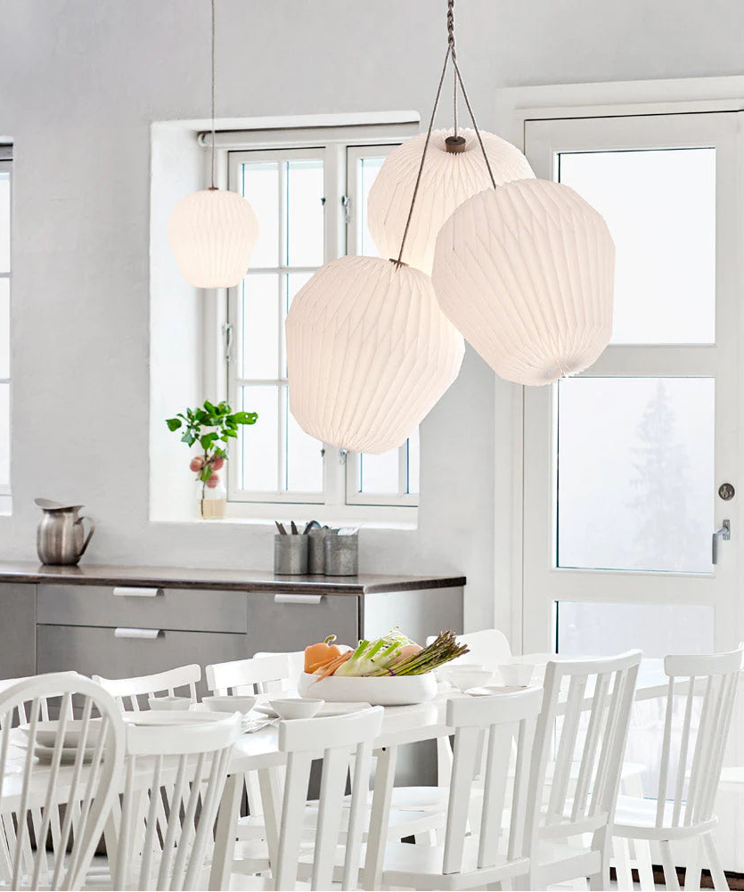Modern kitchen with white dining table and chairs, and pendant lights.